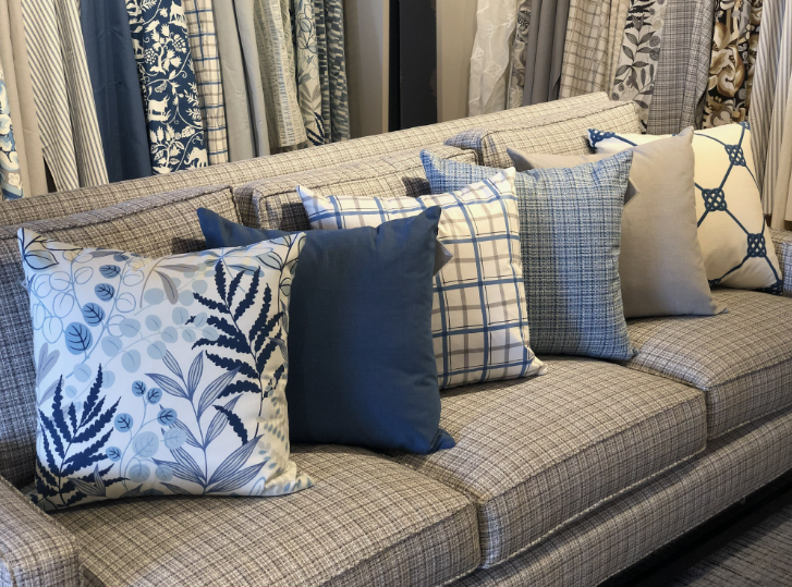 A gray tweed sofa styled with a collection of blue and white patterned accent pillows, showcasing an expert approach to how to decorate when everything doesn't match.