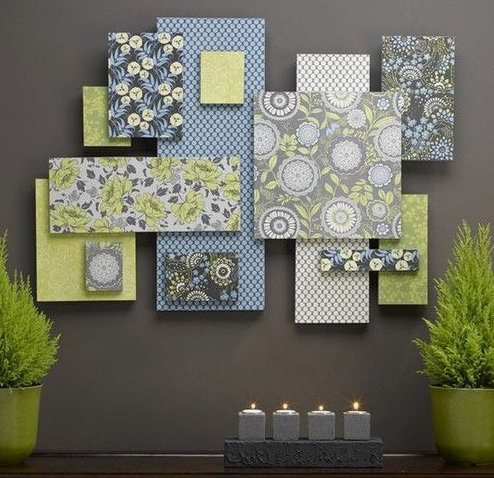 A collection of rectangular panels upholstered in various green and grey patterned fabrics, arranged artfully on a dark wall, demonstrating cheap DIY crafts on a budget.
