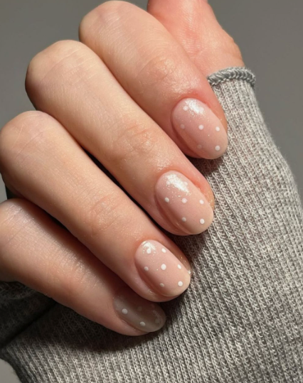 Short neutral glossy nails with delicate white polka dots, presenting a playful yet professional option for office-friendly nail designs.