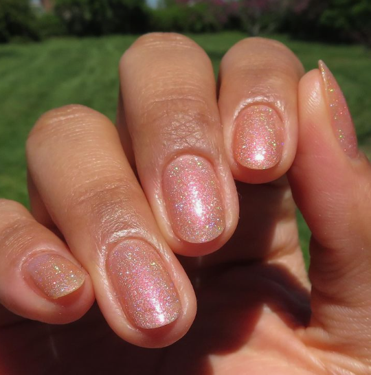Short oval sheer peach-pink holographic glitter nails catching the sunlight, offering a subtle yet radiant touch for office-friendly nail designs.