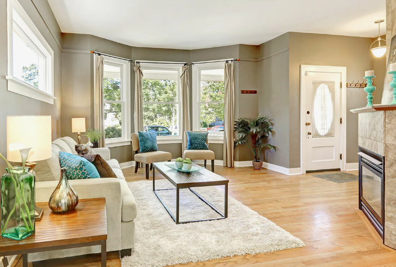 How to Make a Boring Room Look Better: 15 Simple Fixes Bright living room with warm hardwood floors, a cozy sofa with teal pillows, a bay window, and a modern coffee table, showcasing design ideas for how to make a boring room look better.