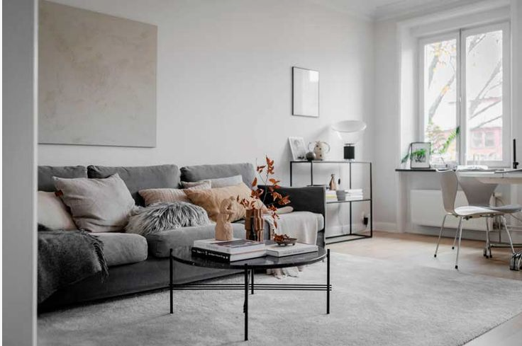How to Make a Boring Room Look Better: 15 Simple Fixes Modern minimalist living room featuring a grey sectional sofa, layered textured pillows, a round coffee table, and soft neutral decor, demonstrating smart styling ideas on how to make a boring room look better.