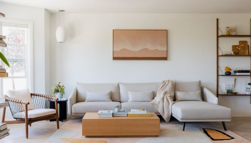 How to Make a Boring Room Look Better: 15 Simple Fixes Modern living room featuring a clean neutral sectional sofa, a wooden coffee table, minimalist wall art, and an open shelving unit, showcasing creative ideas on how to make a boring room look better.