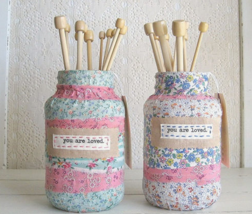 20 No-Sew DIY Crafts for Adults Two glass jars covered in floral fabric and accented with "you are loved" labels, filled with wooden knitting needles, showcasing charming no-sew DIY crafts for adults.