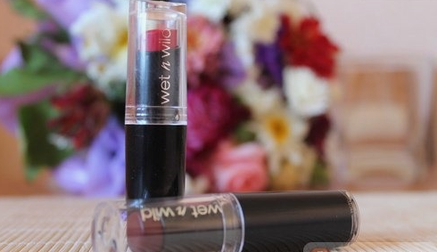 Two Wet n Wild MegaLast lipsticks standing and lying horizontally with clear caps against a soft blurred floral backdrop, highlighting best drugstore beauty products under $20.