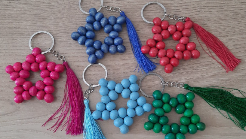 A collection of five star-shaped keychains made from colorful wooden beads and matching thread tassels, presented as a quick craft project under the keyphrase one hour crafts.