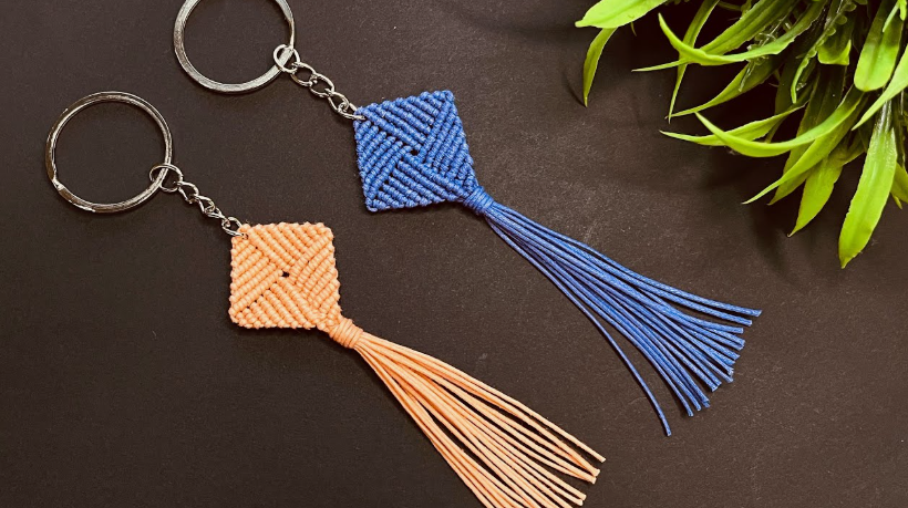 A pair of handmade macrame keychains in blue and peach, featuring diamond-shaped woven knots and flowing fringe tassels, presented as a quick craft project under the keyphrase one hour crafts.