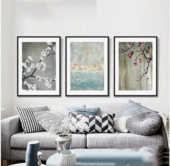 A modern living room styled with a grey sofa, patterned throw pillows, and a trio of framed botanical and abstract art prints hanging on the wall, presented as an interior decoration project under the keyphrase one hour crafts.