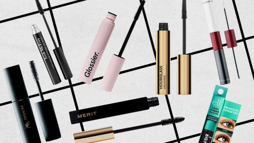 Beauty Products You Actually Need: A Minimalist Guide to Your Beauty Collection Flat lay assortment of top-rated mascaras for beauty products you actually need, featuring popular tubes and wands from brands like Glossier, Merit, and Hourglass on a geometric grid background.