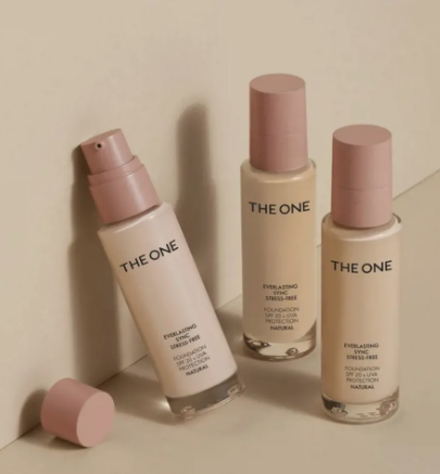 Beauty Products You Actually Need: A Minimalist Guide to Your Beauty Collection Flat lay arrangement of The One Everlasting Sync foundation bottles featuring pink caps and pump dispensers on a neutral background, highlighting beauty products you actually need.
