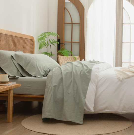 spring living room decor featuring a cozy bed styled with sage green linen bedding, a wooden headboard, and natural textures