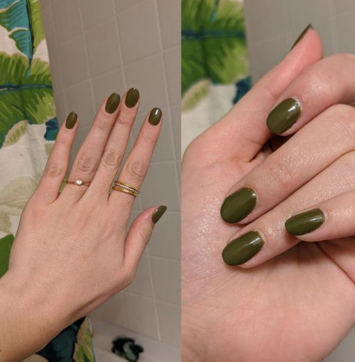 A close-up of a hand wearing dainty gold rings, showcasing elegant short nails for women over 50 polished in a glossy, earthy olive green.