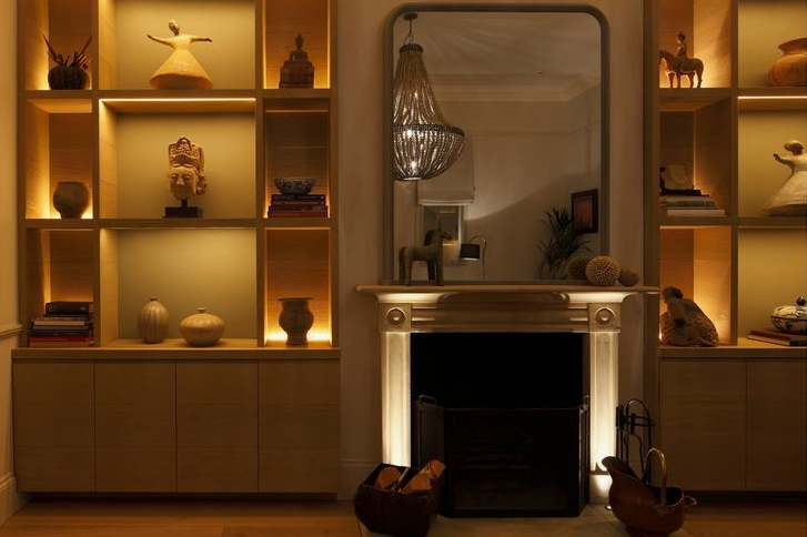 spring living room decor featuring built-in wooden shelving units illuminated with warm accent lighting and styled with sculptures and pottery