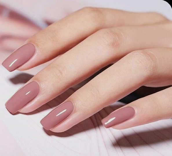 25 Nail Colors That Make Hands Look Younger A close-up shot of well-manicured hands wearing glossy dusty rose polish, showcasing nail colors that make hands look younger.