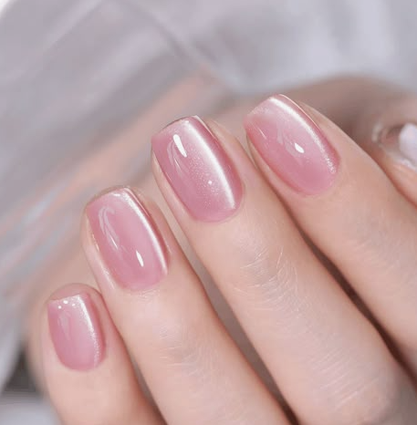 25 Nail Colors That Make Hands Look Younger A close-up of short, squared peach-toned nails holding a matching polish bottle, demonstrating nail colors that make hands look younger.