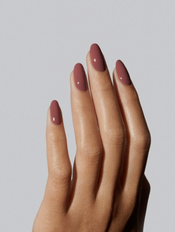 25 Nail Colors That Make Hands Look Younger An elegant hand with glossy almond-shaped rose-brown nails against a neutral background, showcasing beautiful nail colors that make hands look younger.