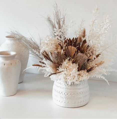spring living room decor featuring a textured white ceramic pot filled with a rich arrangement of dried florals, pampas grass, and earthy botanicals