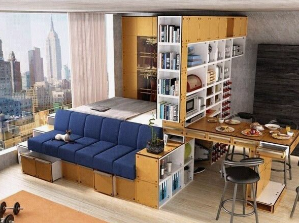 A multi-functional urban apartment featuring a convertible blue sofa, integrated modular shelving, a pull-out dining table, and a raised bed overlooking a city skyline, showcasing space-saving small apartment decor ideas.