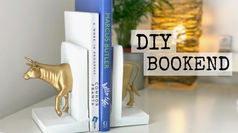 A custom-made DIY bookend featuring a split gold bull figurine emerging from white bookends holding a row of books, showcasing brilliant DIY crafts that look expensive.
