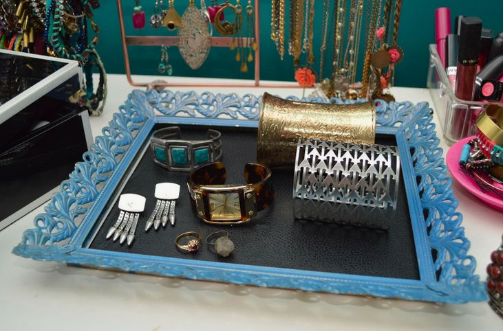 An ornate, blue-painted picture frame converted into a chic jewelry tray lined with leather, displaying bracelets, rings, and earrings, showcasing wonderful DIY crafts that look expensive.