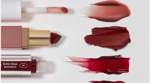 2026 Beauty Trends That Are Actually Worth Trying Swatches of lip products including a nude gloss, a deep red satin lipstick, and a glossy berry tint, showcasing top 2026 beauty trends for statement lip colors.