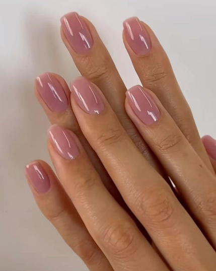 30 Classy Nail Colors for Mature Hands Hands featuring classy nail colors for mature hands, showcasing short, glossy jelly-pink square nails against a clean white background.