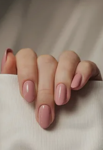 30 Classy Nail Colors for Mature Hands Hands showcasing classy nail colors for mature hands, featuring glossy dusty rose oval nails resting against a soft white fabric.