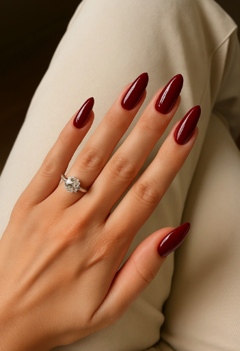 30 Classy Nail Colors for Mature Hands A hand showcasing classy nail colors for mature hands, featuring glossy dark burgundy almond nails accented with a sparkling diamond ring.