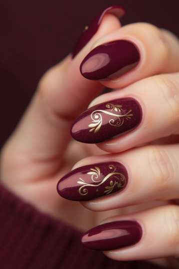 30 Classy Nail Colors for Mature Hands Hands showcasing classy nail colors for mature hands, featuring glossy dark burgundy oval nails detailed with elegant gold filigree scrollwork.