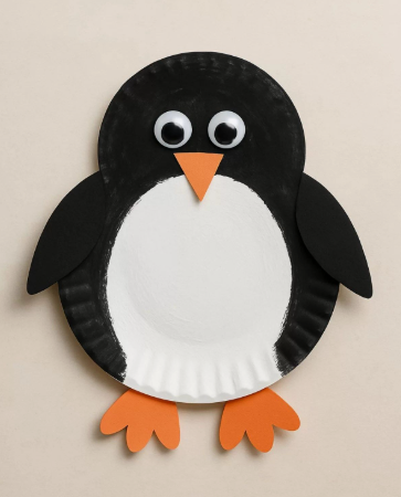 A cute paper plate penguin craft with black paper wings, googly eyes, and orange flippers, an easy winter activity for preschool seasonal crafts.