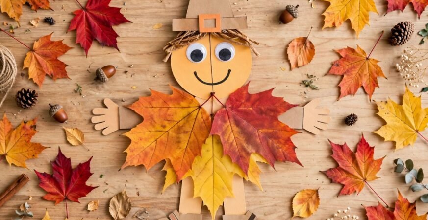 Cardboard scarecrow dressed in fall leaf clothing with googly eyes, a charming project for October crafts for kids.