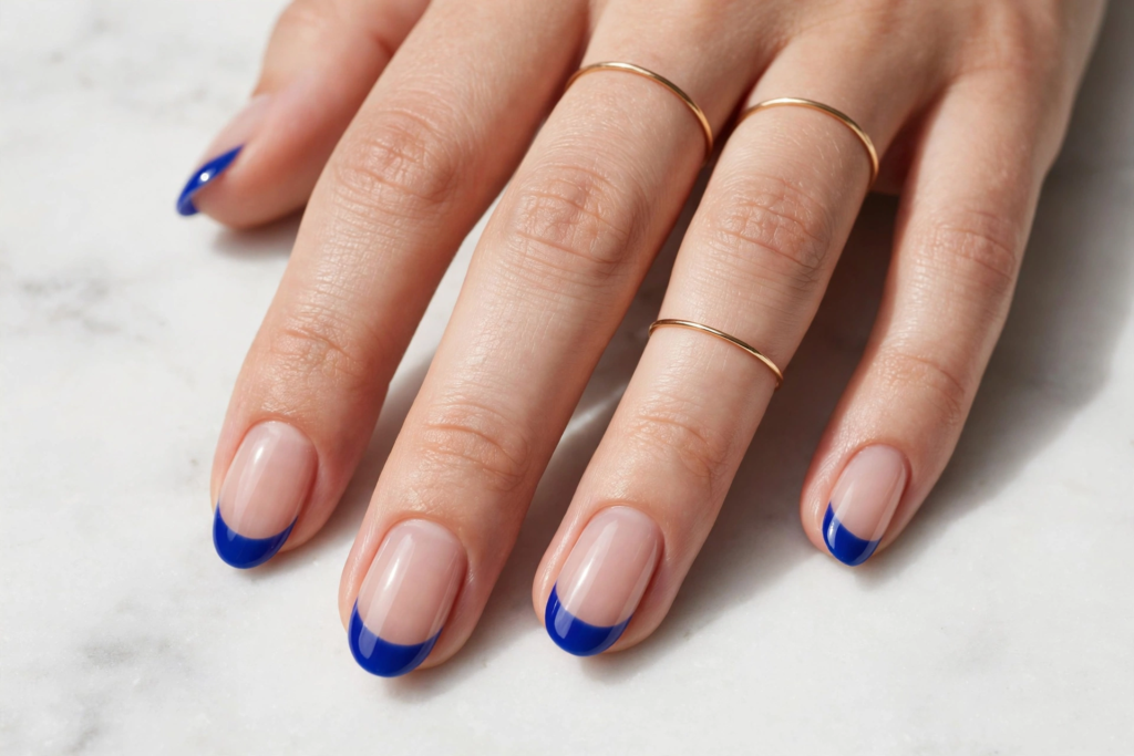 Bold cobalt blue french nails ideas featuring glossy oval-shaped nails with vivid royal blue French tips on a nude base.   