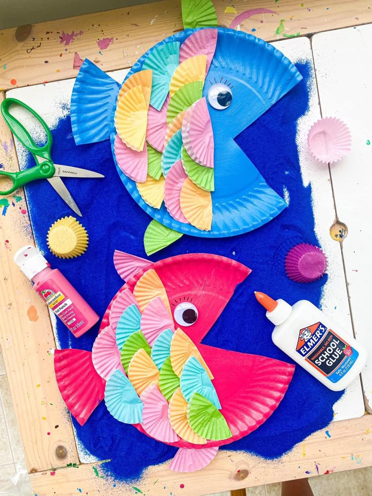 24 Preschool Seasonal Crafts for Spring, Summer, Fall & Winter Two colorful paper plate fish decorated with folded cupcake liner scales, a creative summer under-the-sea project for preschool seasonal crafts.