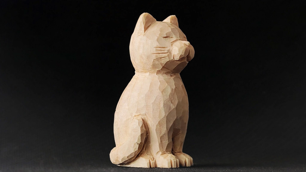 20 Nostalgic Crafts Making a Comeback in 2026 Hand-carved wooden cat figurine with faceted whittling textures against a dark background, highlighting nostalgic crafts 2026 woodcarving and woodworking ideas.