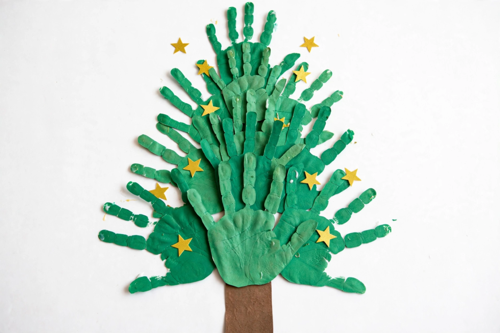 24 Preschool Seasonal Crafts for Spring, Summer, Fall & Winter A green handprint Christmas tree collage decorated with yellow star stickers and a brown trunk, a festive winter idea for preschool seasonal crafts.