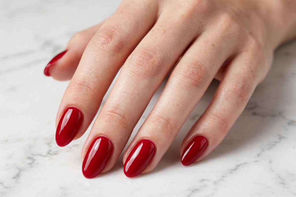 Classic glossy cherry red almond nails on a white marble background as nail inspo 2026.   