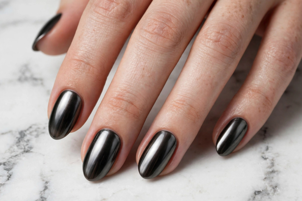 Glossy metallic gunmetal chrome oval nails on a marble background as nail inspo 2026.   