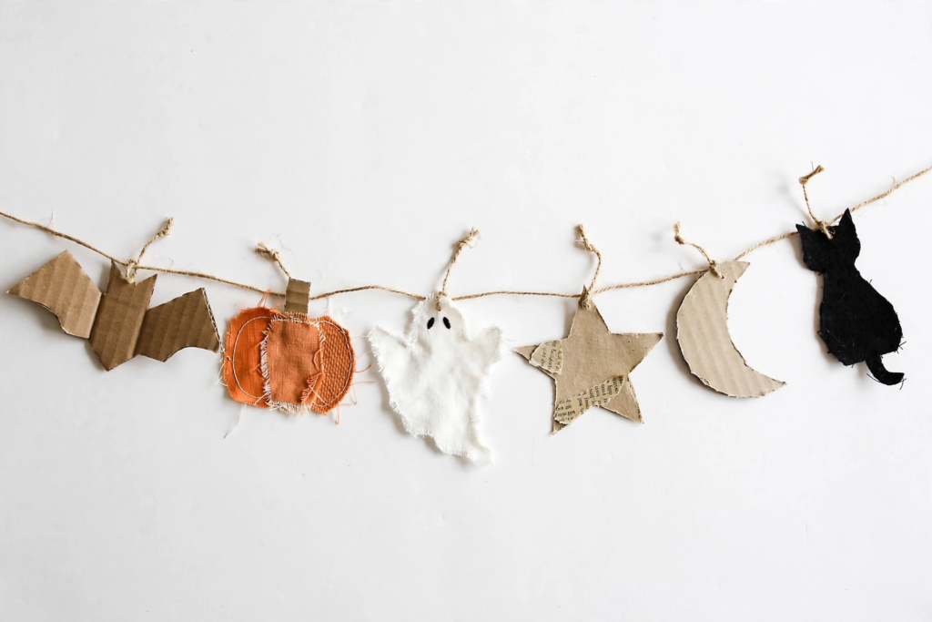 Handmade rustic garland made from cardboard, fabric, and twine featuring Halloween shapes for simple Halloween decorations and crafts.   