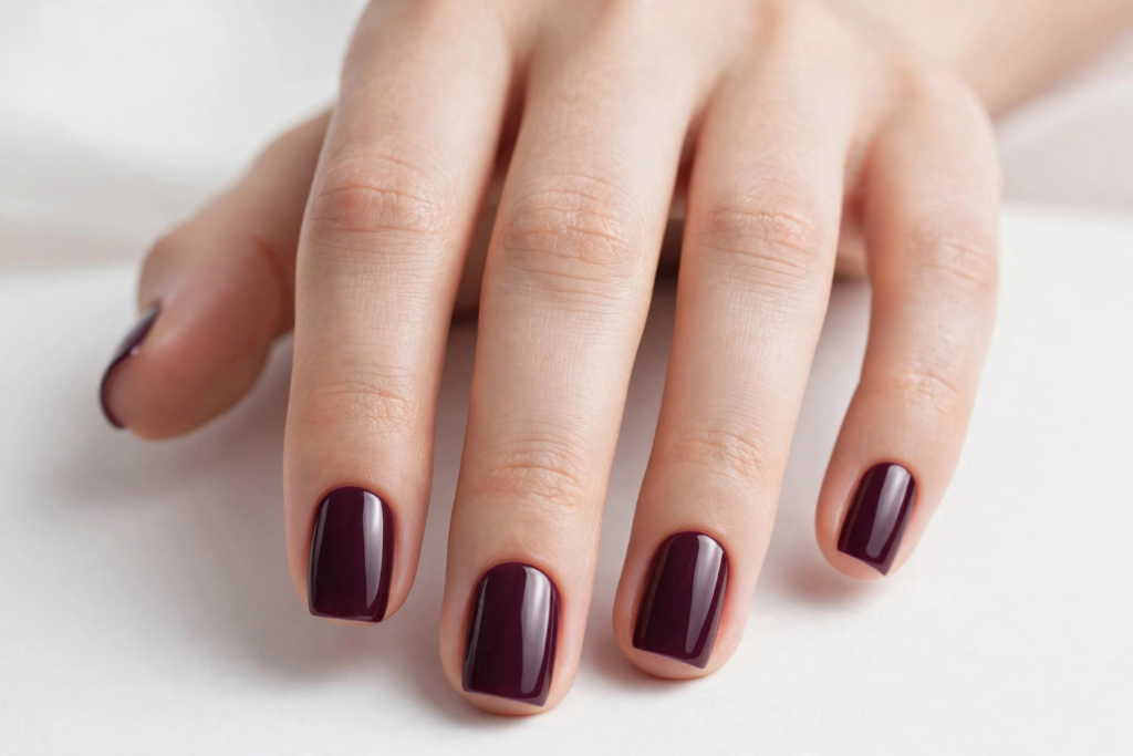 High-shine deep plum nails with a classic square shape, showcasing a trendy fall plum manicure for autumn 2026.