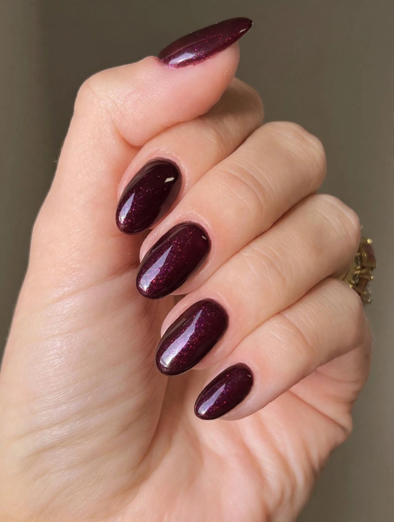 Glossy oval-shaped nails painted in a rich plum burgundy shade with subtle micro-shimmer for fall plum nails 2026.