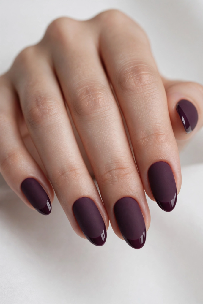 Matte deep plum oval nails finished with glossy French tips for an elegant contrast in fall plum nails 2026.   