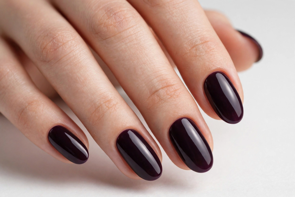 High-shine oval nails painted in an ultra-dark blackberry plum polish for a classic fall plum nails 2026 manicure.   