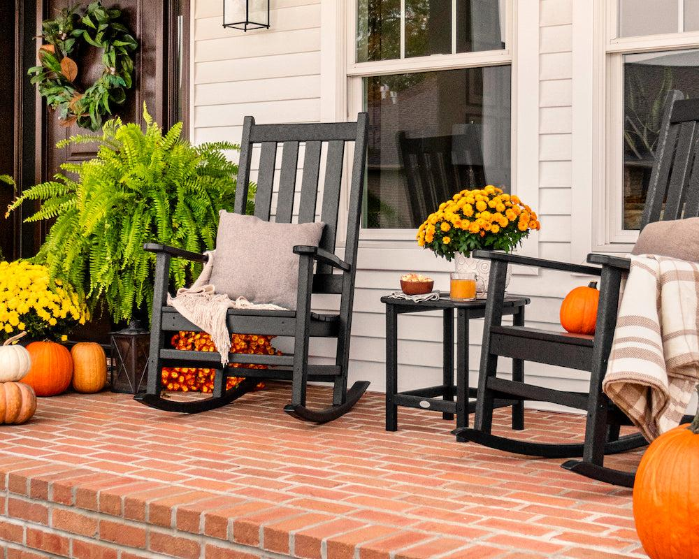Fall Decorating Ideas 2026 for Every Room in Your Home Cozy front porch styled with fall decorating ideas 2026, featuring black rocking chairs, orange pumpkins, and yellow potted chrysanthemums.