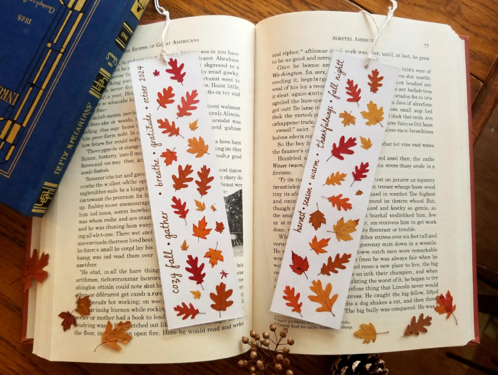 DIY laminated autumn leaf bookmarks resting on an open book as simple fall crafts for beginners.   