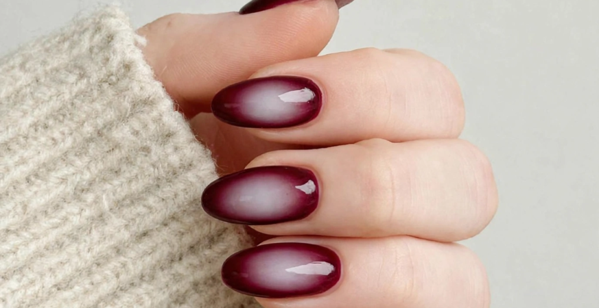 Aura Nails 2026: 25 Dreamy Designs to Try Burgundy aura nails featuring glossy oval tips with deep wine-red edges framing a diffused milky white center, trending for fall and winter 2026 nail designs.